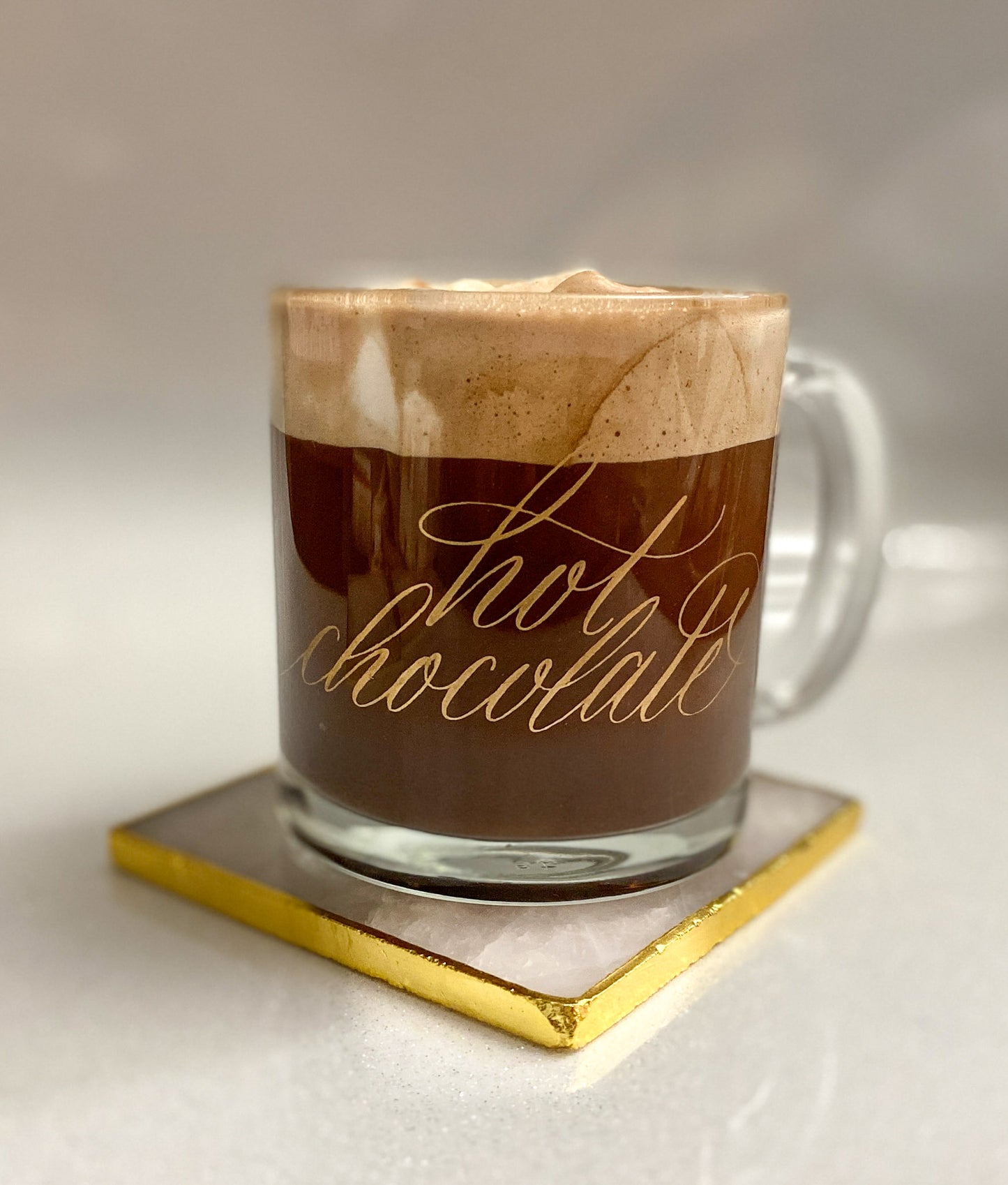 Gold hot chocolate calligraphy glass mug on a pink and gold coaster