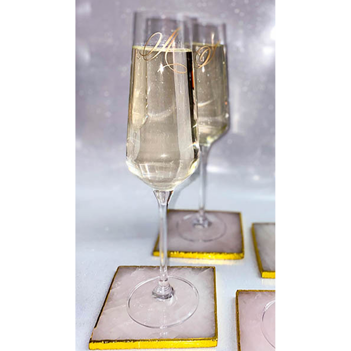Gold Monogram Engraved Champagne Flutes On Pink Rose Quartz Coasters